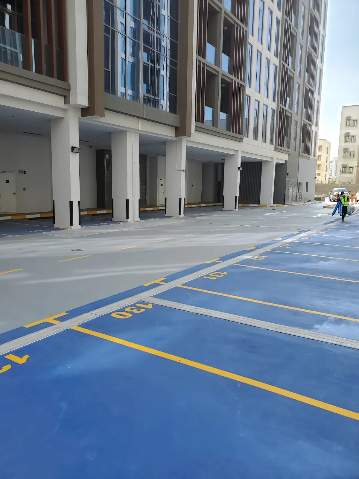 Blue coated parking bays with yellow line marking and bay numbers beside a residential building