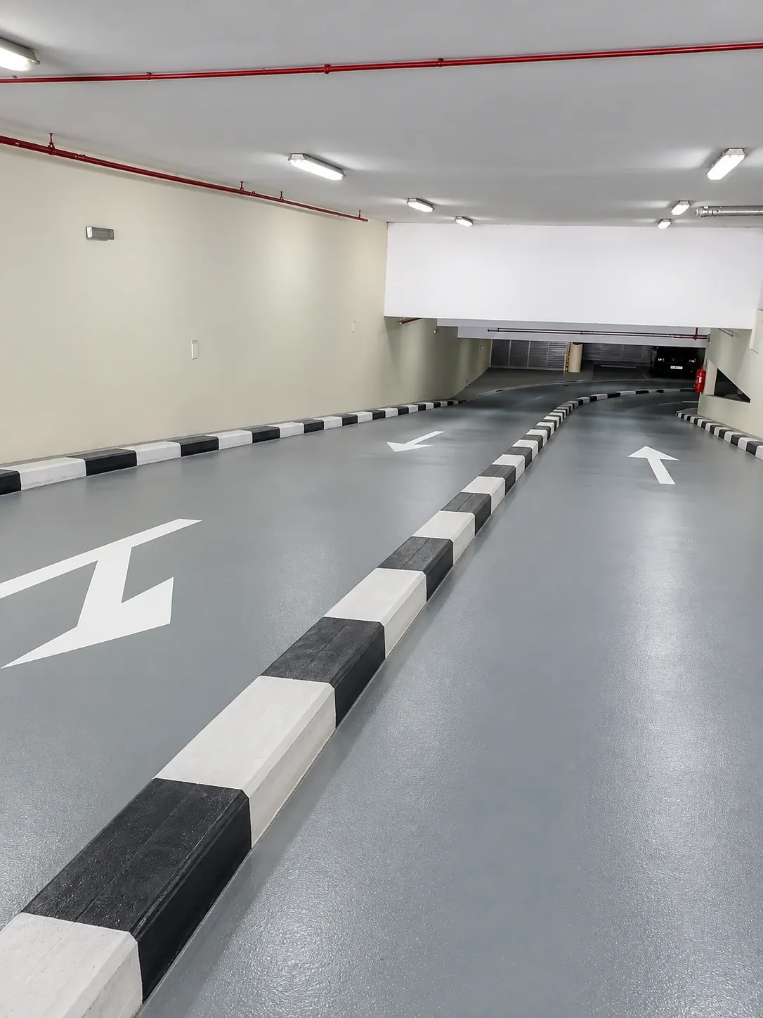 Vehicle access ramp with a textured grey coating, painted kerbs and directional arrows